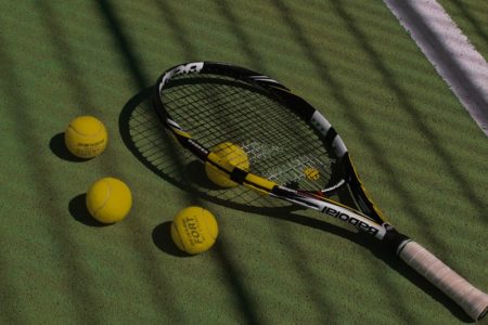 a tennis racket and four tennis balls on a court