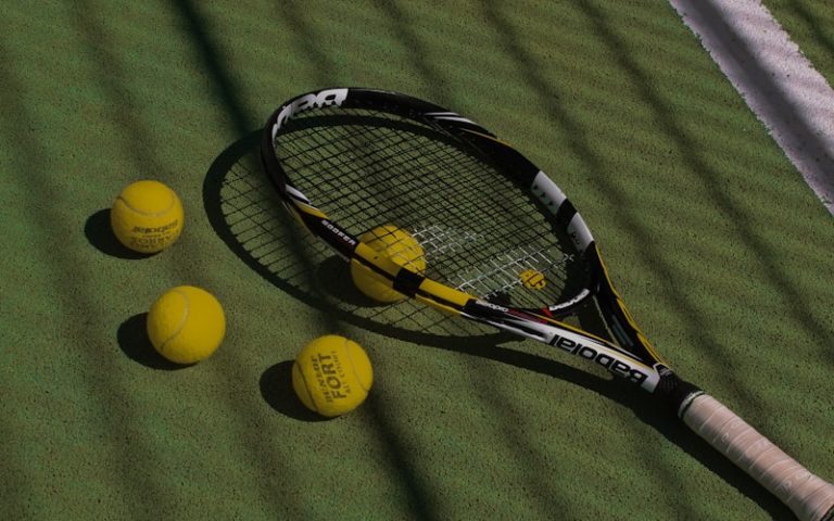 a tennis racket and four tennis balls on a court