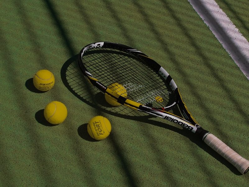 a tennis racket and four tennis balls on a court